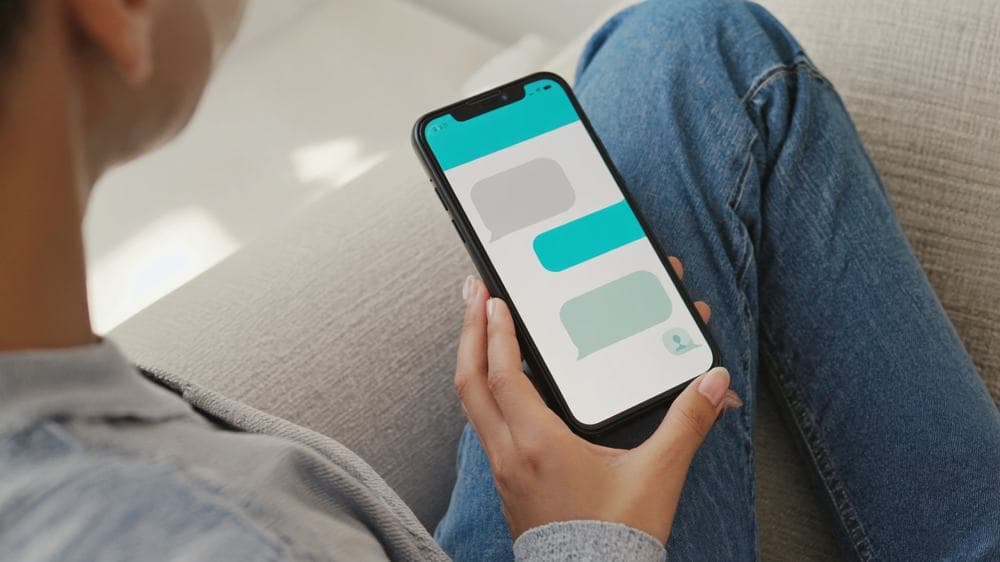 Someone sitting on a sofa holding a phone with a conversation open